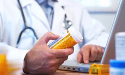 Pharmacist with bottles and laptop