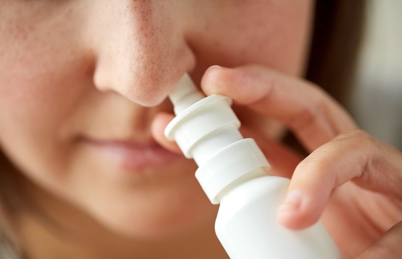 close up of sick woman using nasal spray