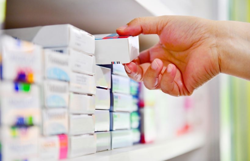 Closeup pharmacist hand holding medicine box in pharmacy drugstore.