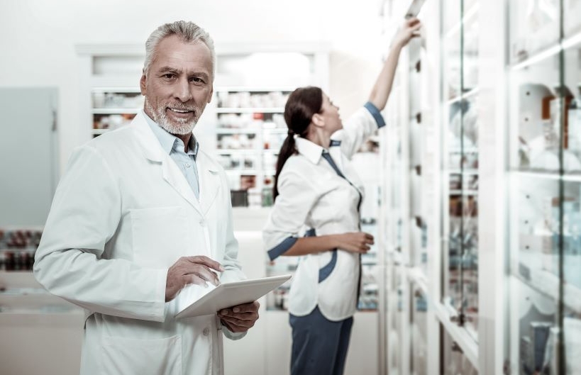 Mature prosperous director of Pharmacy holding digital tablet 