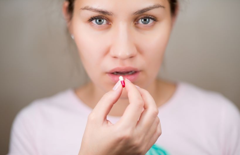 Young woman about to take a color pill